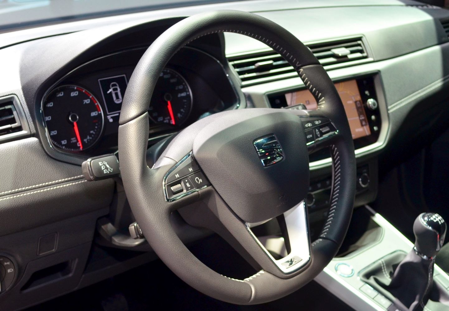 Steering wheel, instrument cluster, and center console with manual gear shift.