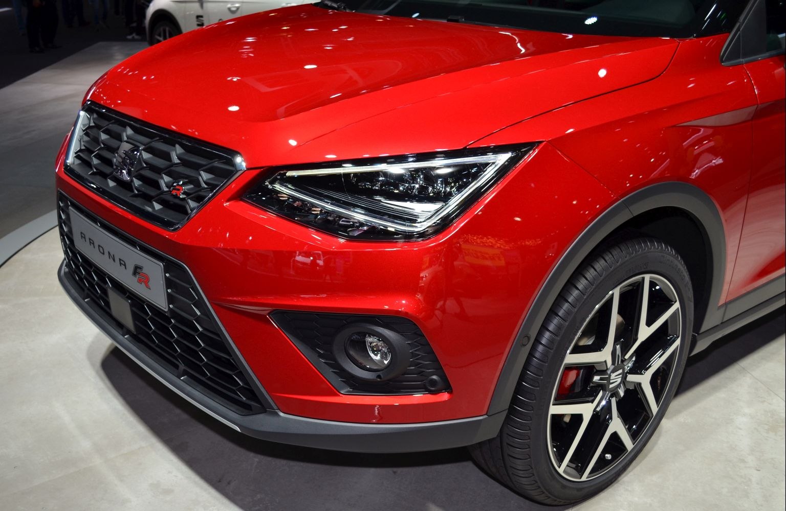 Sharp front grille, intricate headlight, and stylish alloy wheel in close-up.