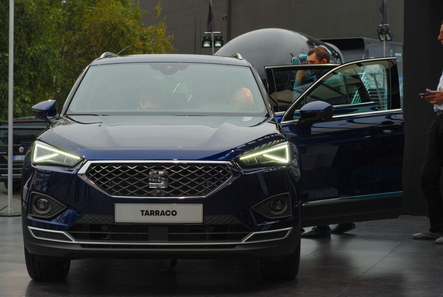 Close-up on illuminated LED headlights and hexagonal grille front fascia.