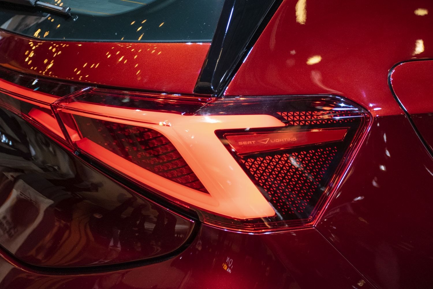 Close-up of futuristic angular tail light with red LEDs on maroon rear panel
