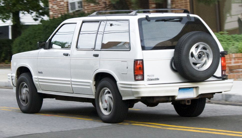 Rear side view of white SUV with rear-mounted spare tire