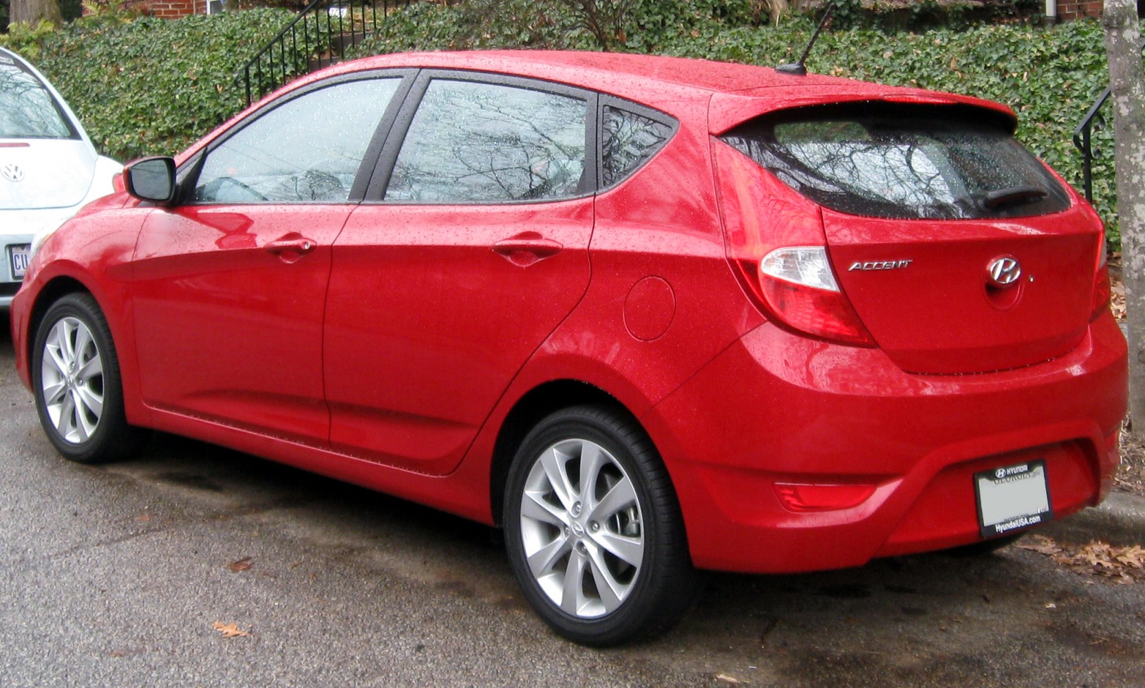 Red hatchback rear side profile with alloy wheels and spoiler