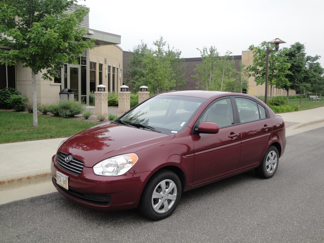 Front side exterior view of compact sedan with rounded headlights and burgundy finish