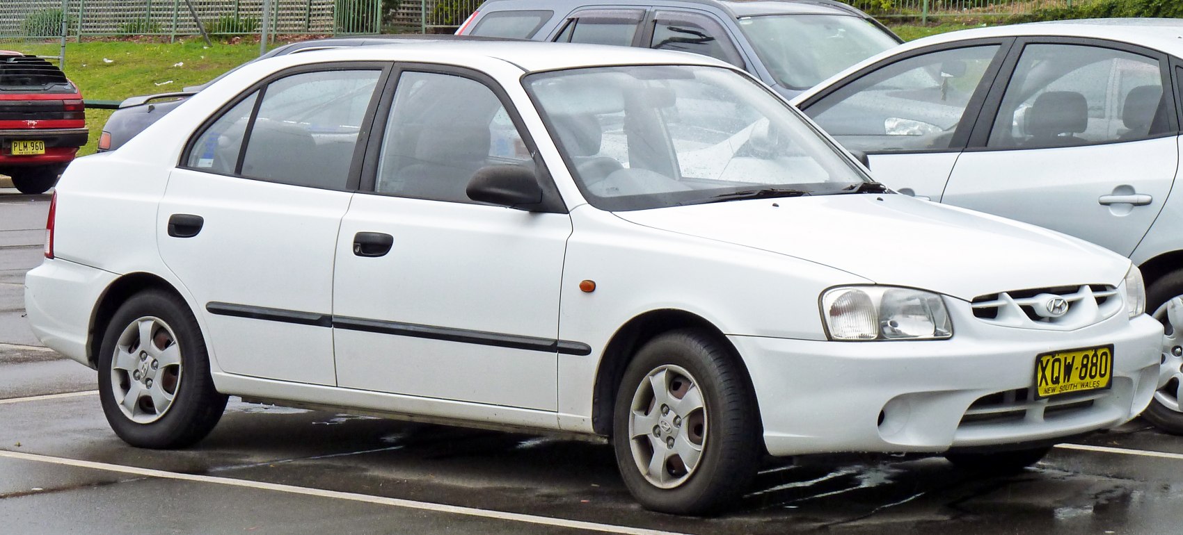 White compact sedan with round headlights and alloy wheels parked outdoors