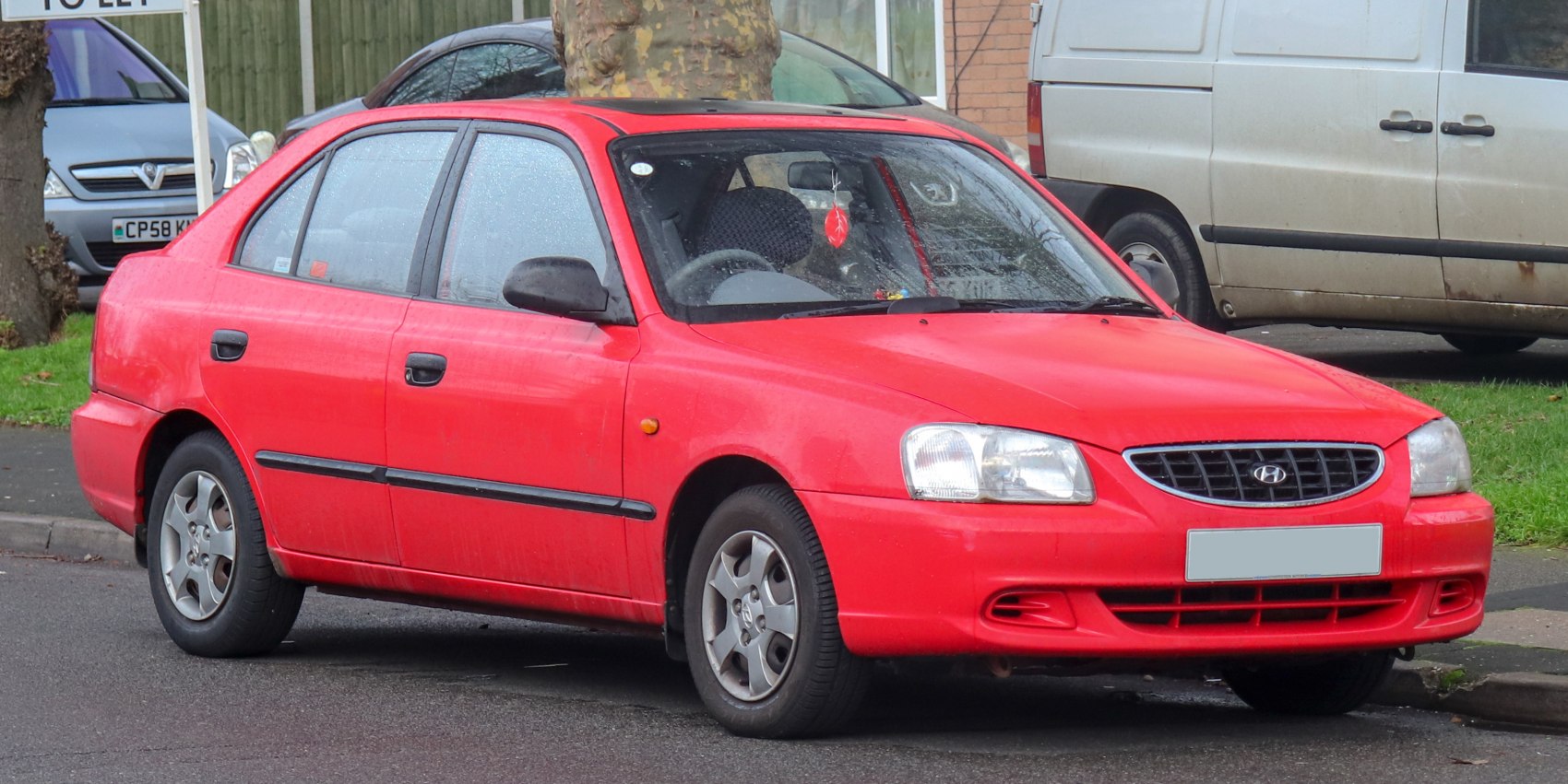 Front-left exterior view of red hatchback with distinctive headlights and body shape