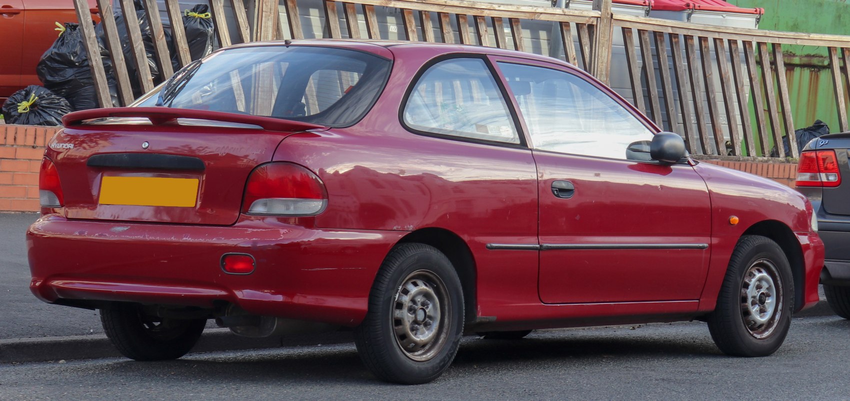 Rear side profile of a compact vintage hatchback with spoiler