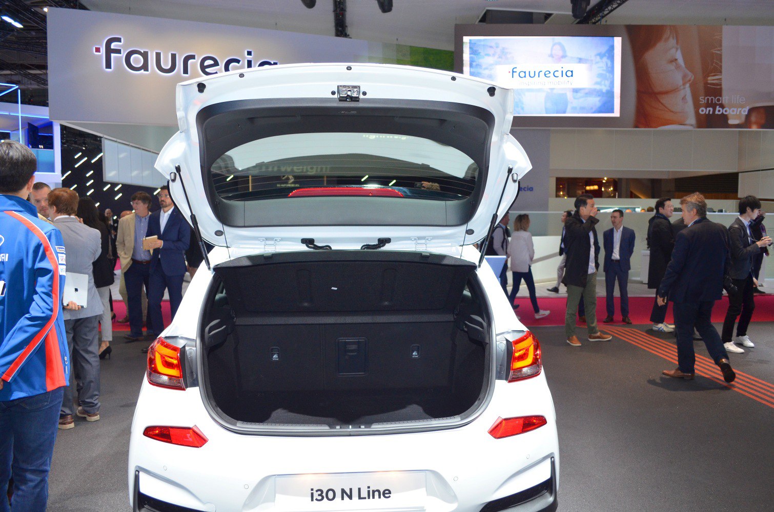Open trunk of a white hatchback showing spacious cargo area and rear taillights.