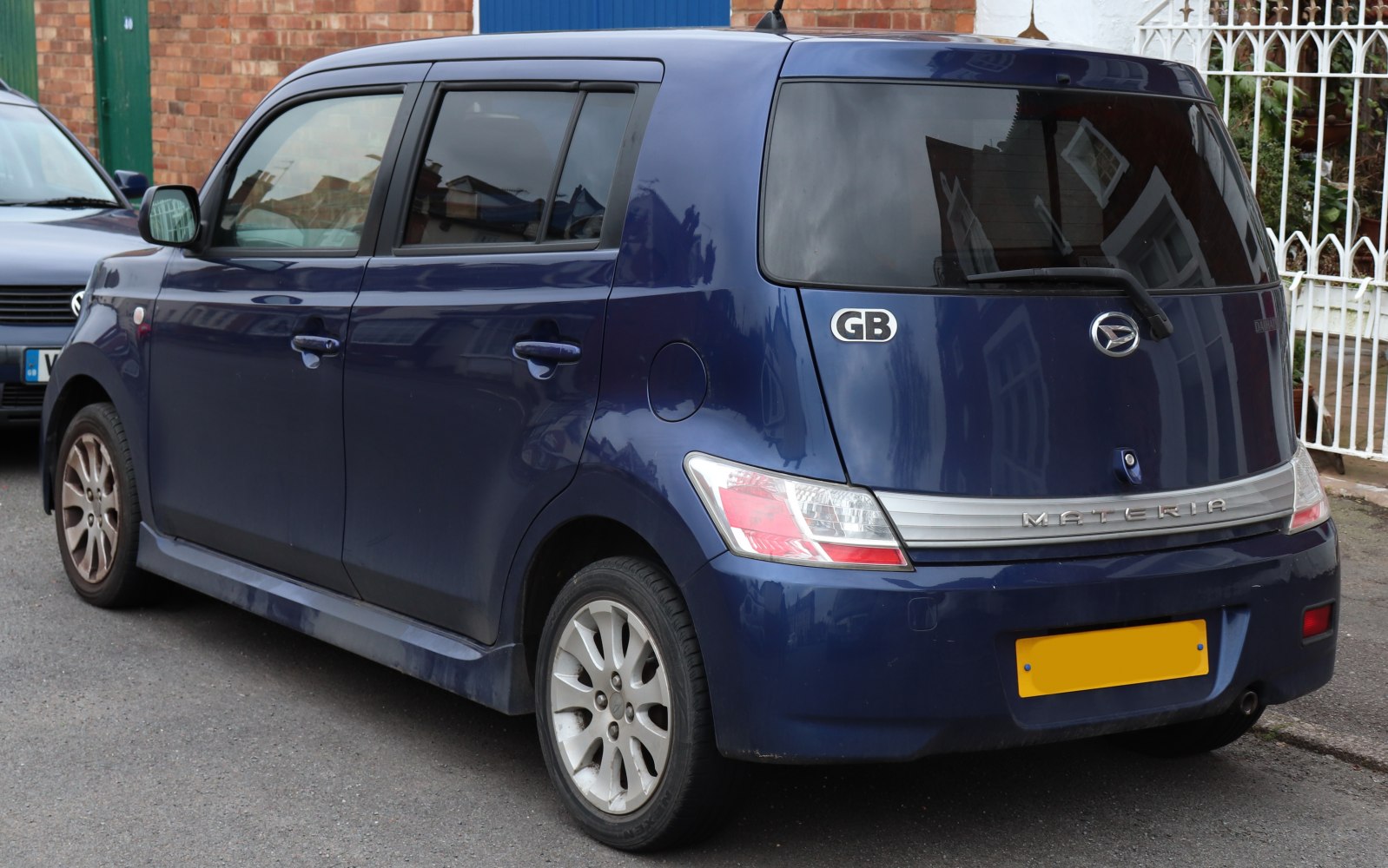 Boxy compact hatchback rear side with unique tail lights and large rear window.