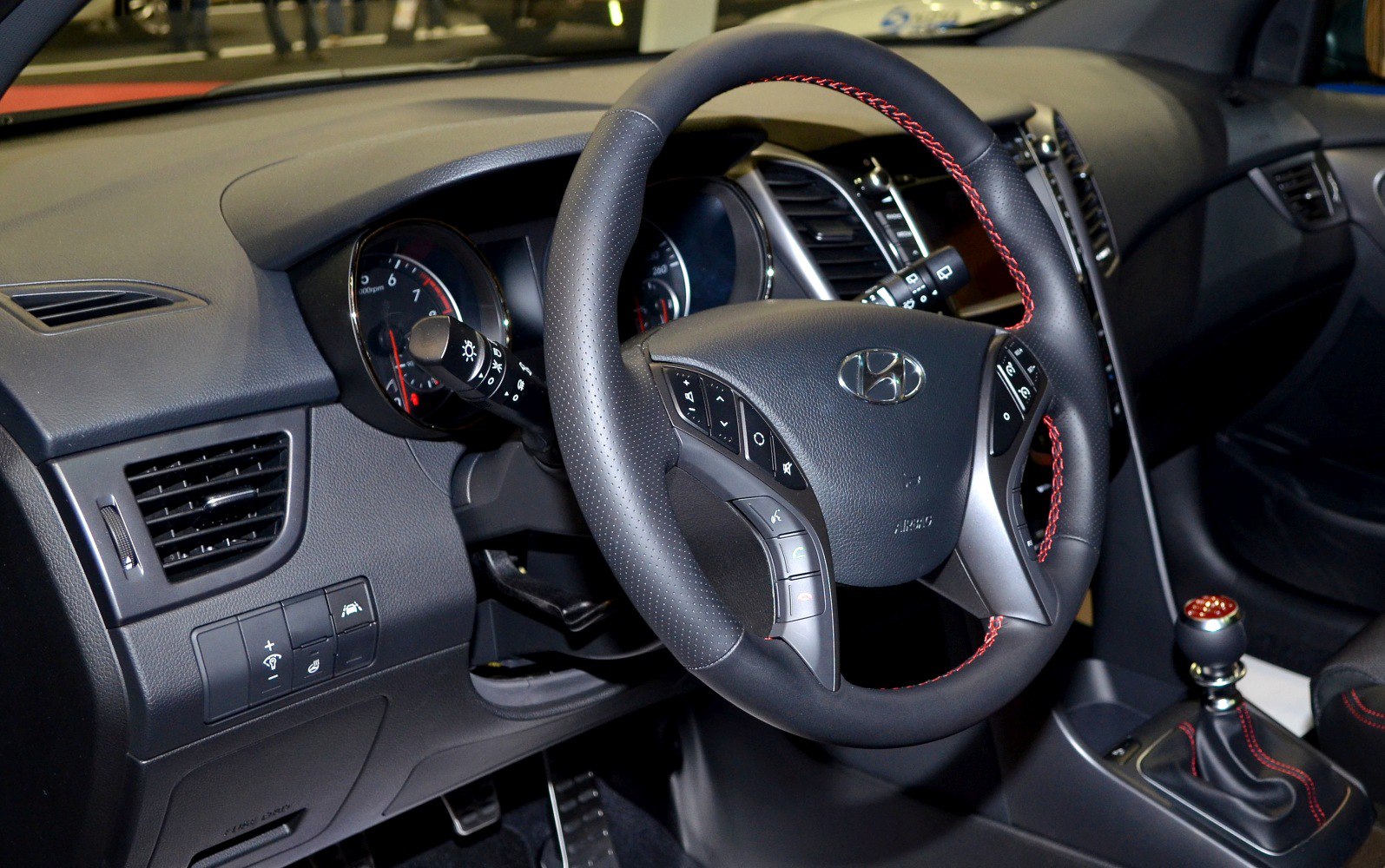 Steering wheel, dashboard controls, and gear shift with red stitching