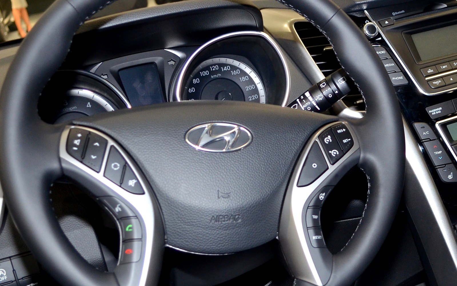 Close-up of steering wheel with control buttons and dashboard speedometer.