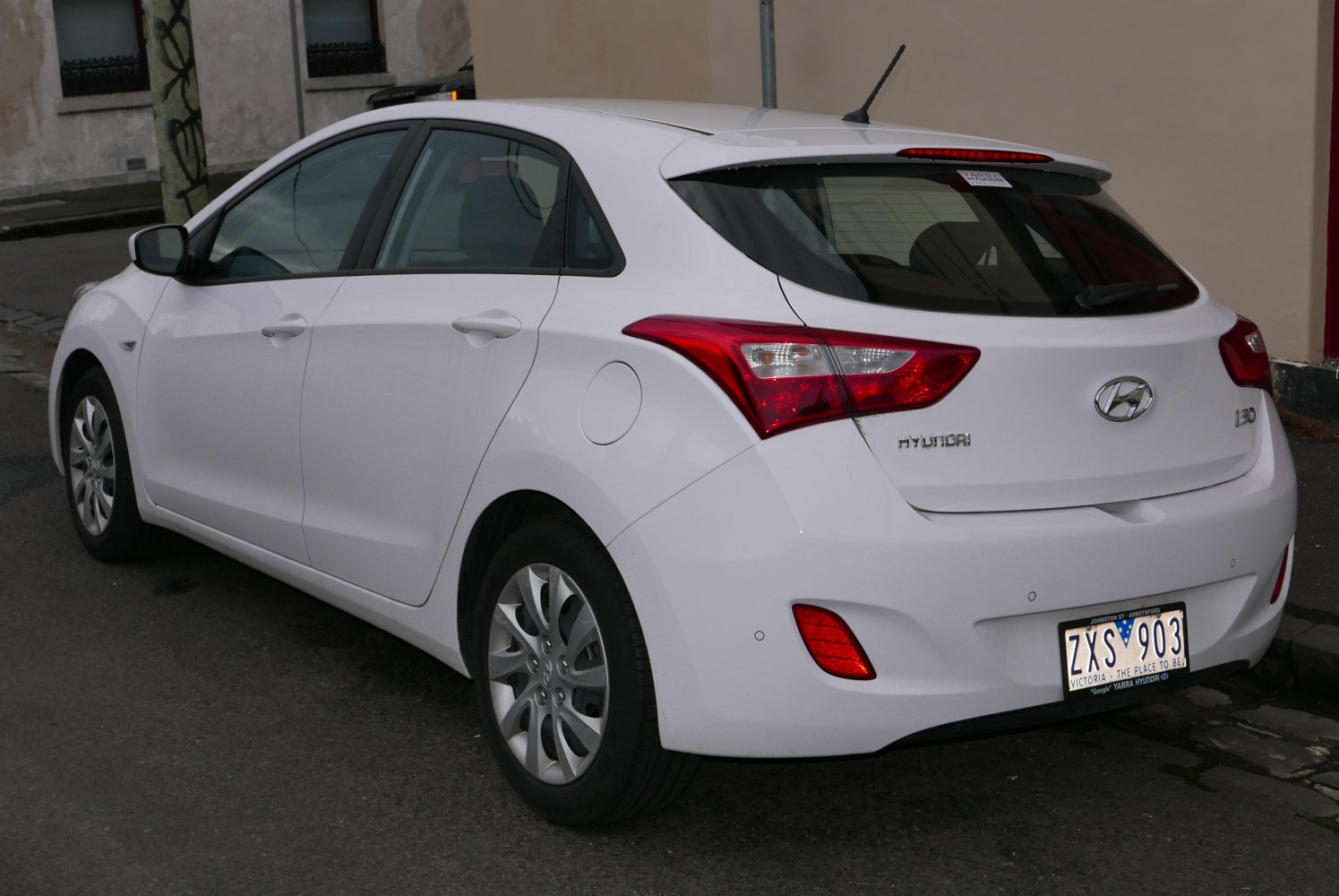 Rear view of a white hatchback showcasing tail lights and compact design