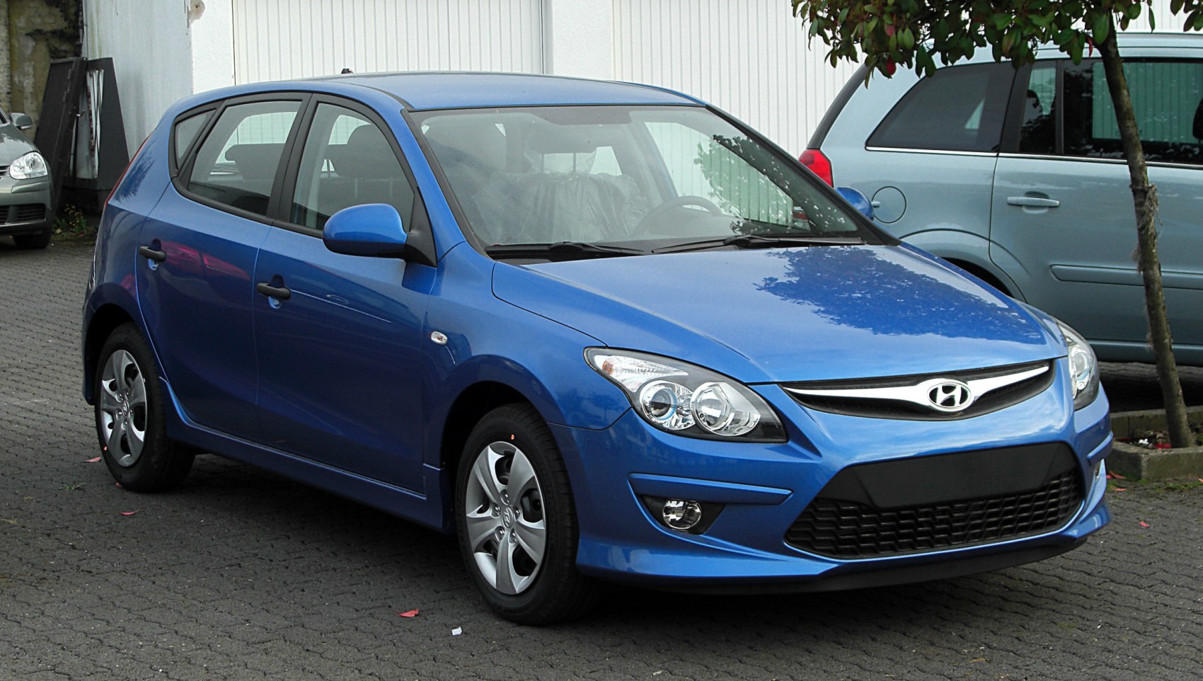 Blue compact hatchback front side view with detailed headlights and grille