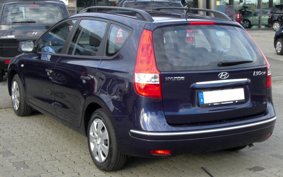 Rear view of a dark blue wagon with roof rails and vertical tail lights