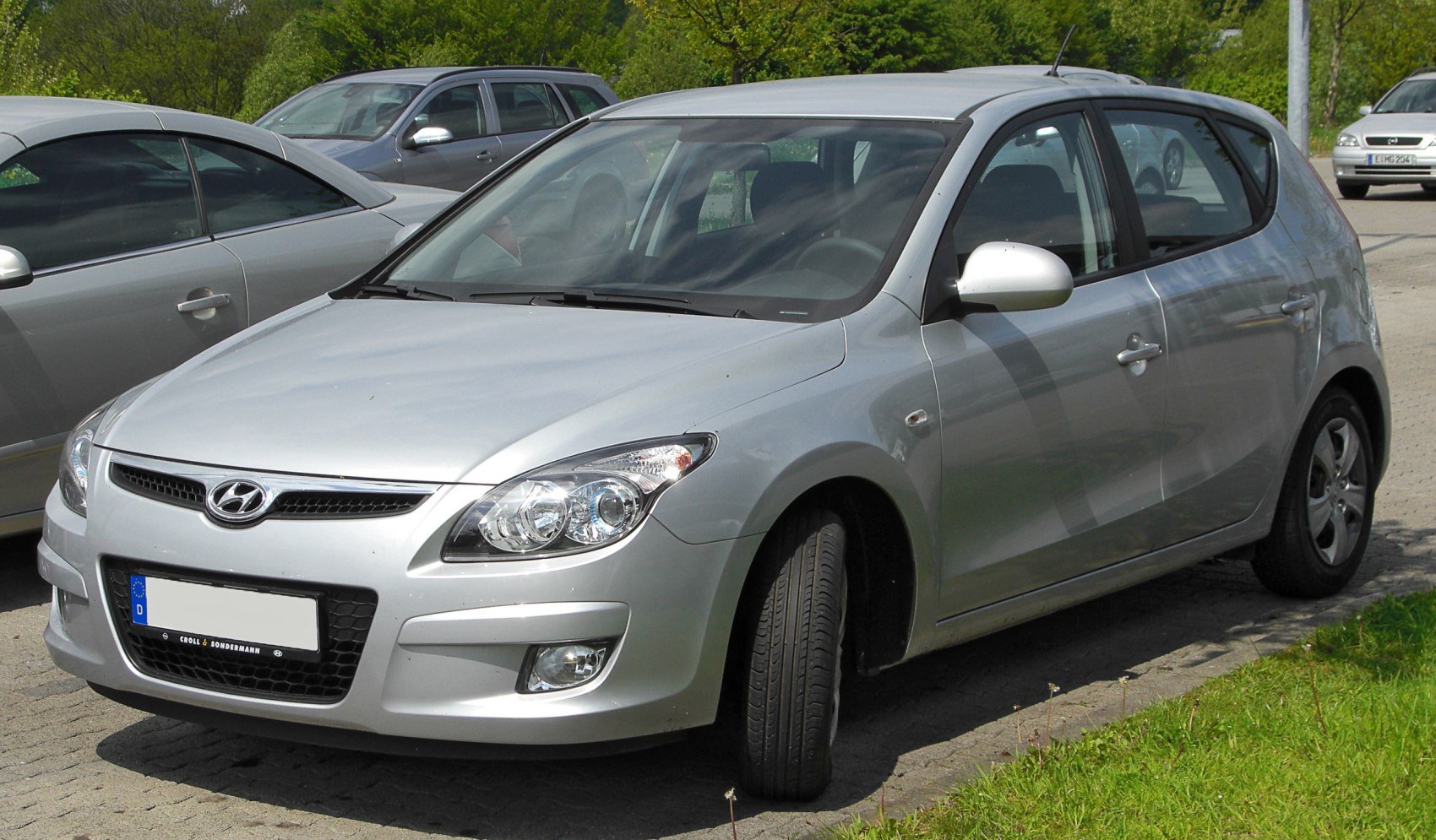 Front-side view of silver hatchback with prominent headlights and grille