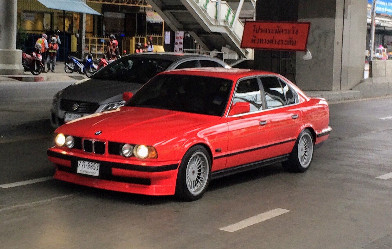Red classic sedan with twin round headlights and Alpina style multi-spoke wheels
