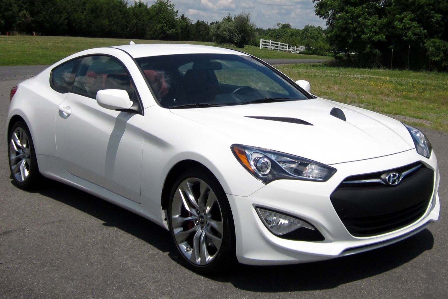 Sporty white coupe with aggressive front grille and bonnet vents
