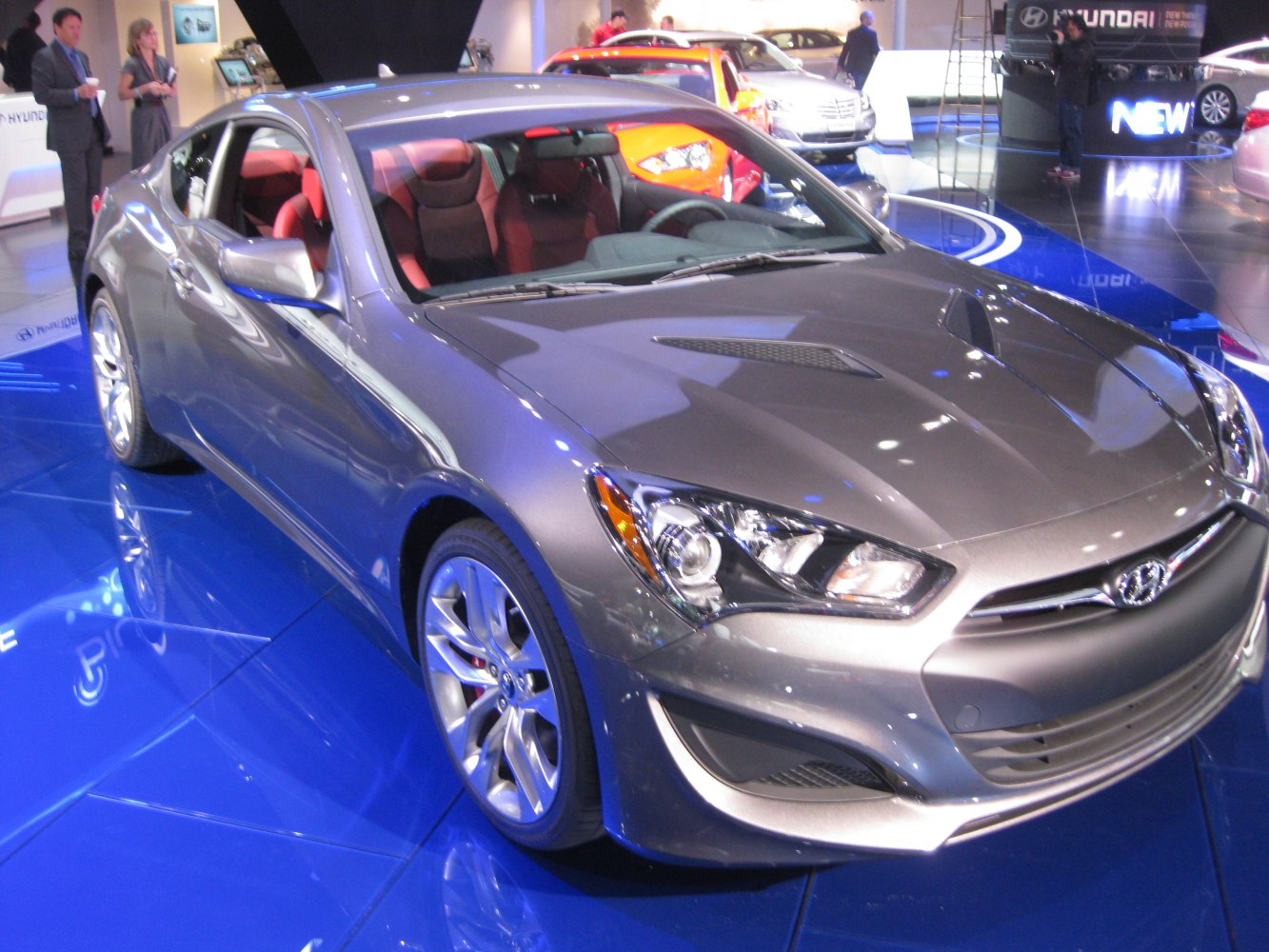 Front side view of a sleek sports coupe with sharp headlights and red interior seats