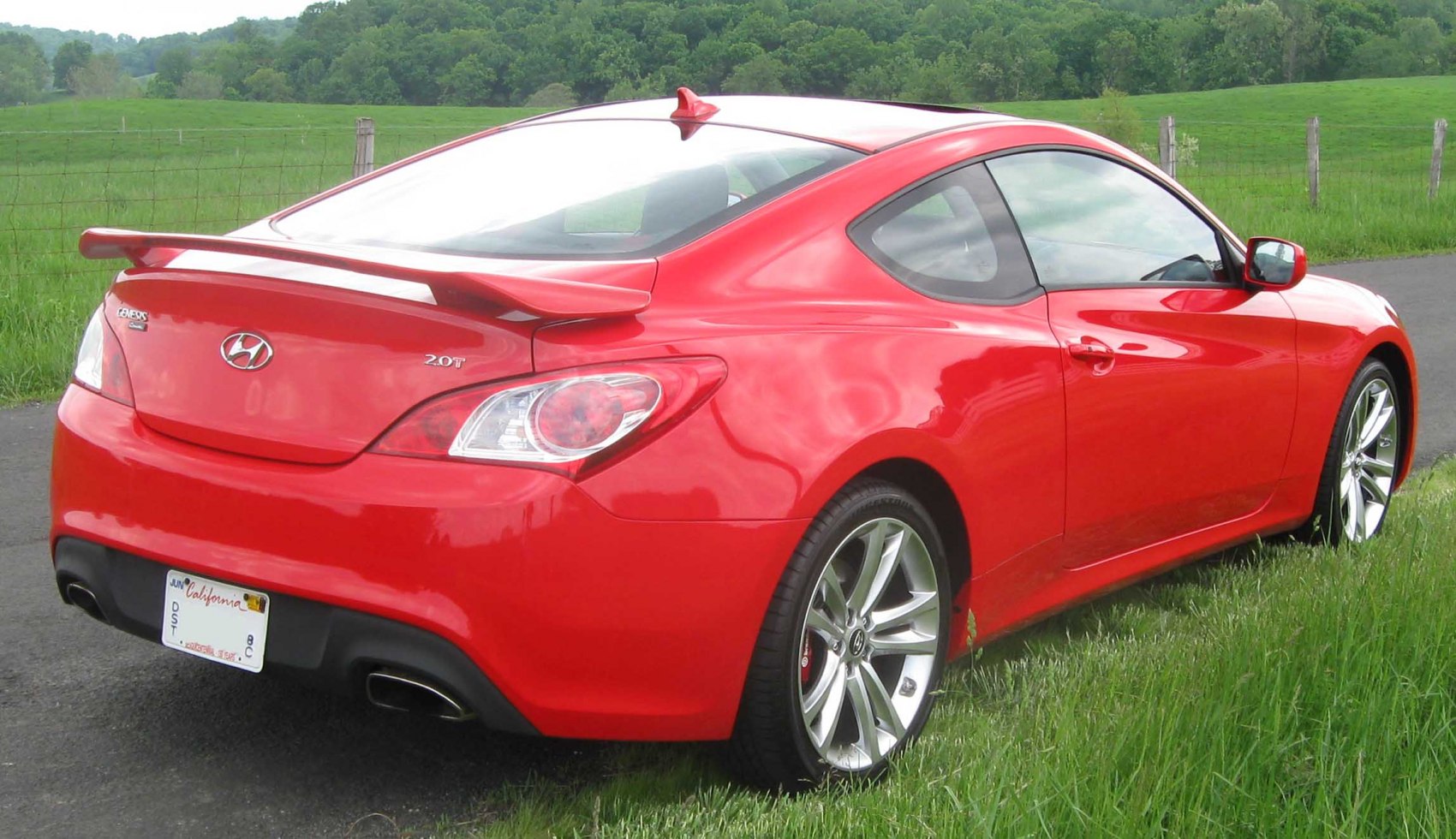 Rear and side view of a red coupe with spoiler and alloy wheels