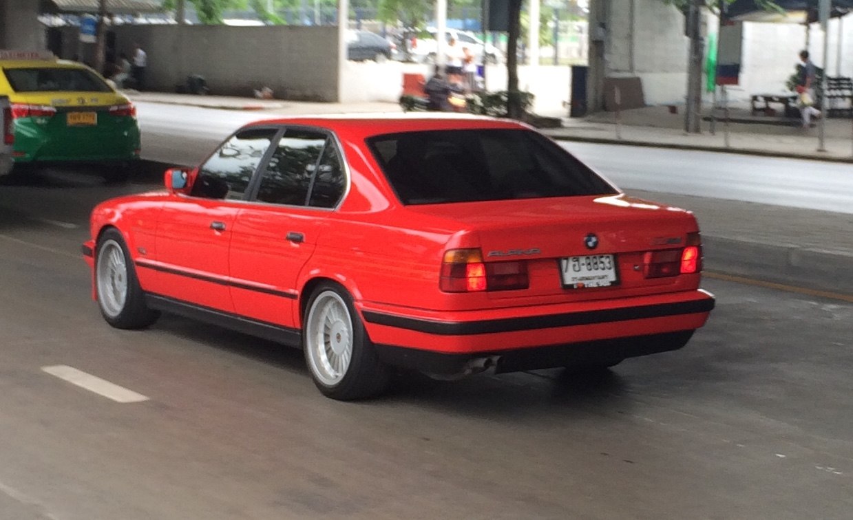Red sedan rear side view with Alpina multi-spoke wheels