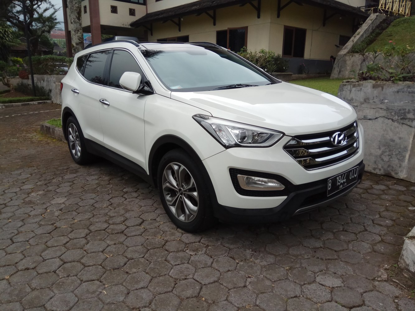 Front and side view of white midsize SUV with distinctive headlights and grille