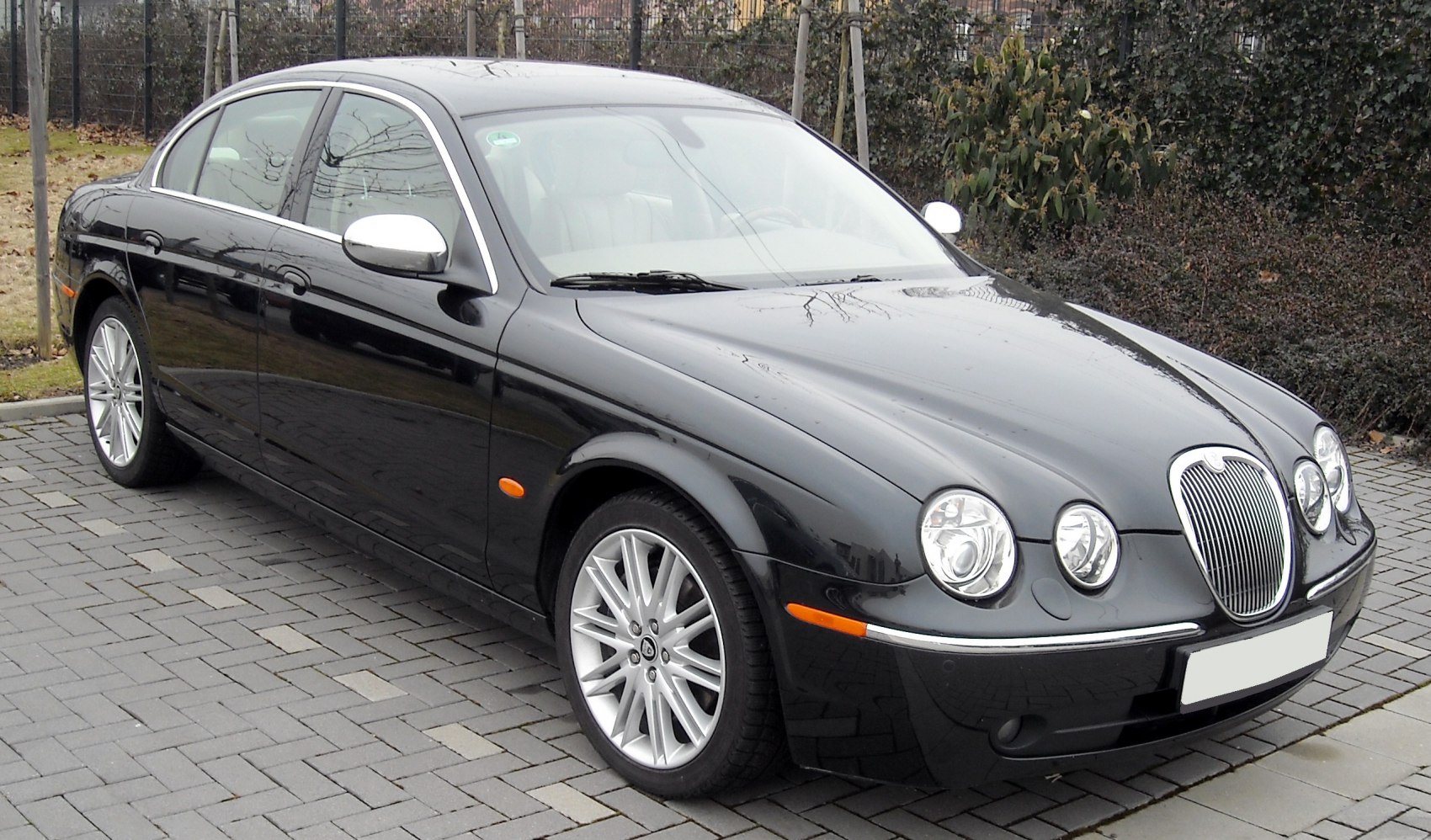 Front view of a black sedan with quad round headlights and chrome side mirrors.