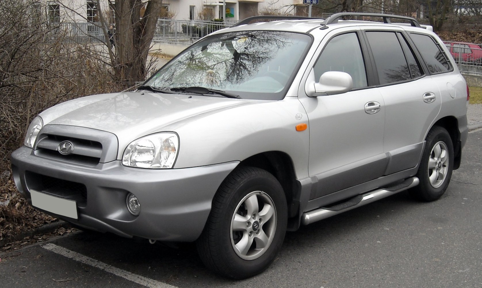 Silver SUV with front grille, roof rails, side steps parked on street