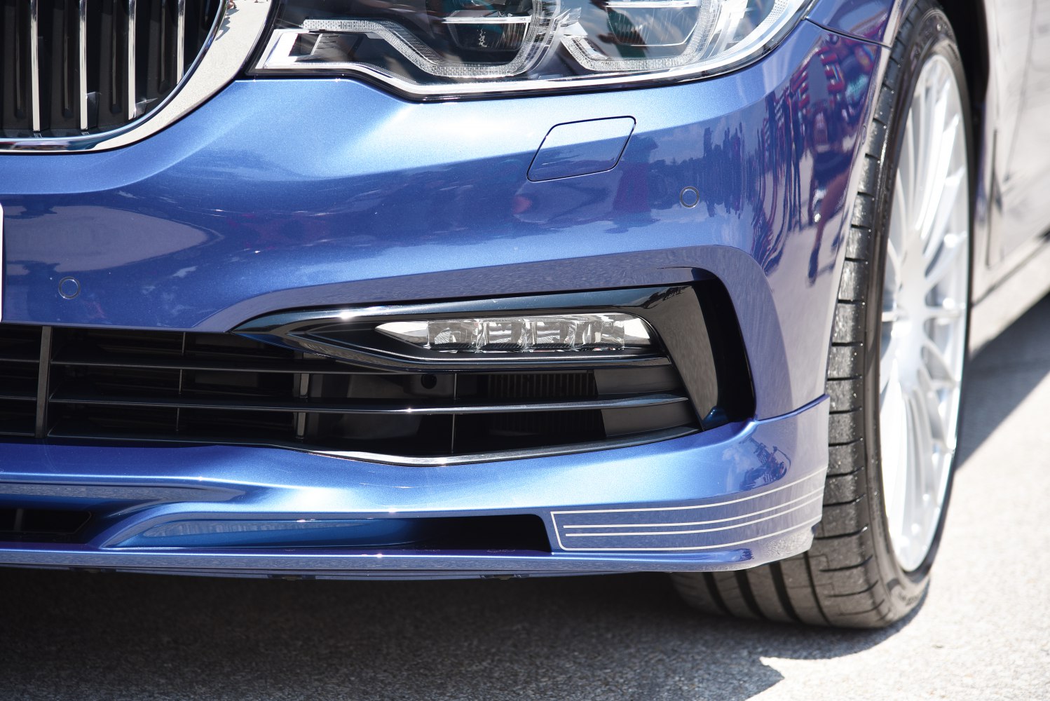 Close-up of front bumper, headlight, grille, and wheel.