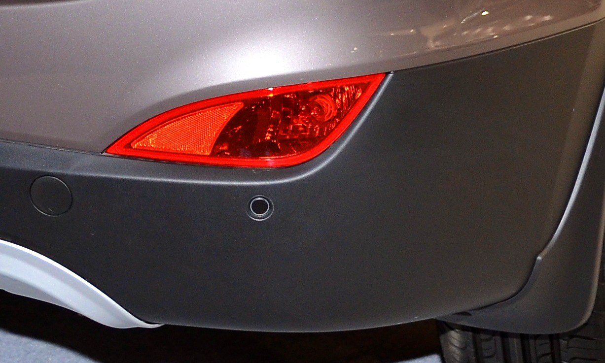 Rear reflector and parking sensor on dark bumper section