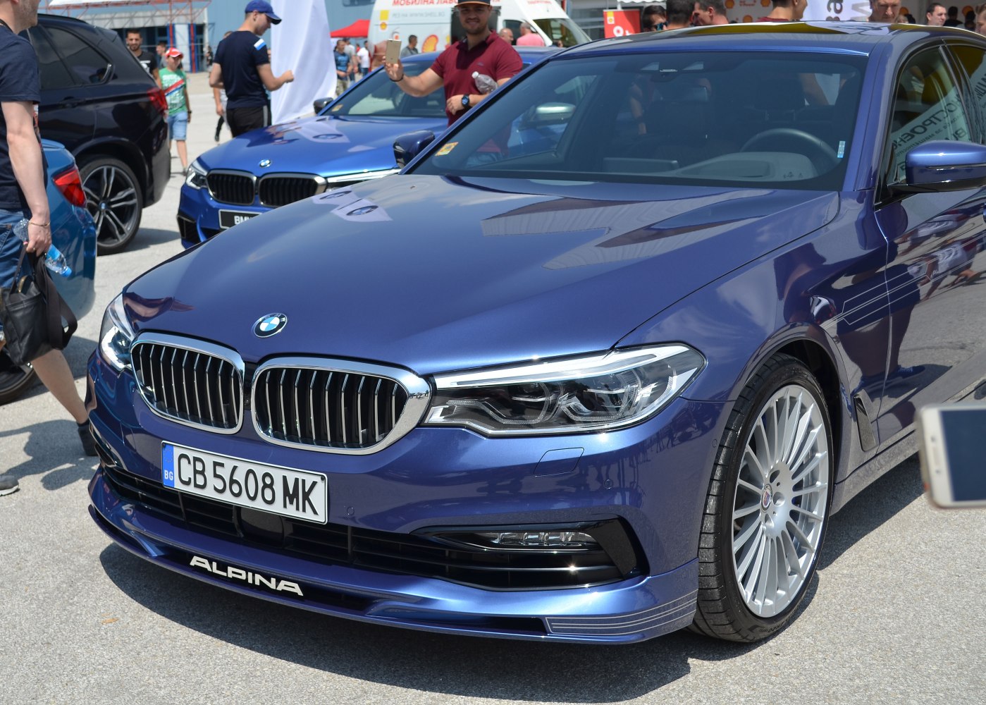 Front view of blue luxury sedan with signature grille and multi-spoke wheels