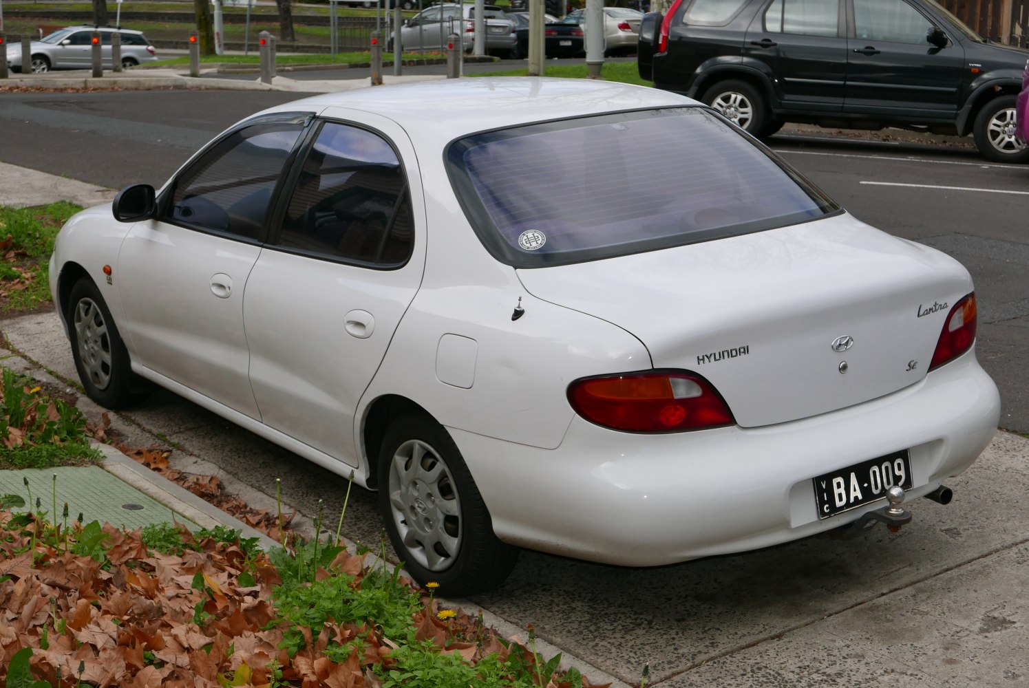 Rear-side view of a white four-door mid-1990s hatchback sedan