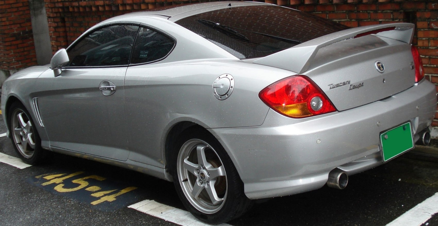 Rear side view of silver coupe with spoiler and alloy wheels