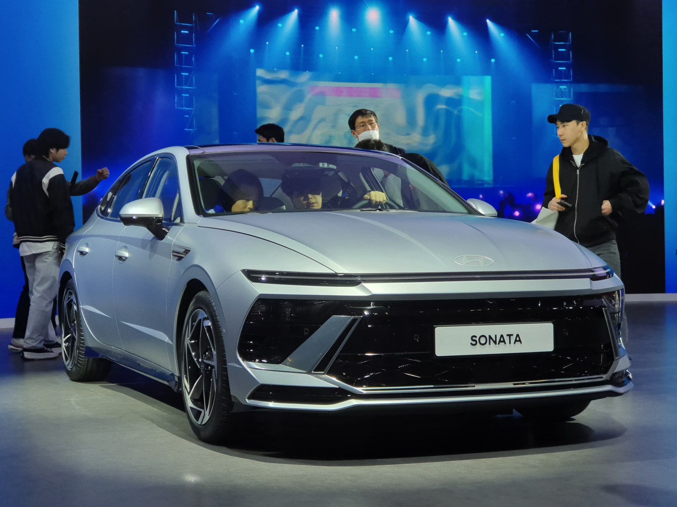 Sleek sedan front with slim LED lights and large glossy grille.