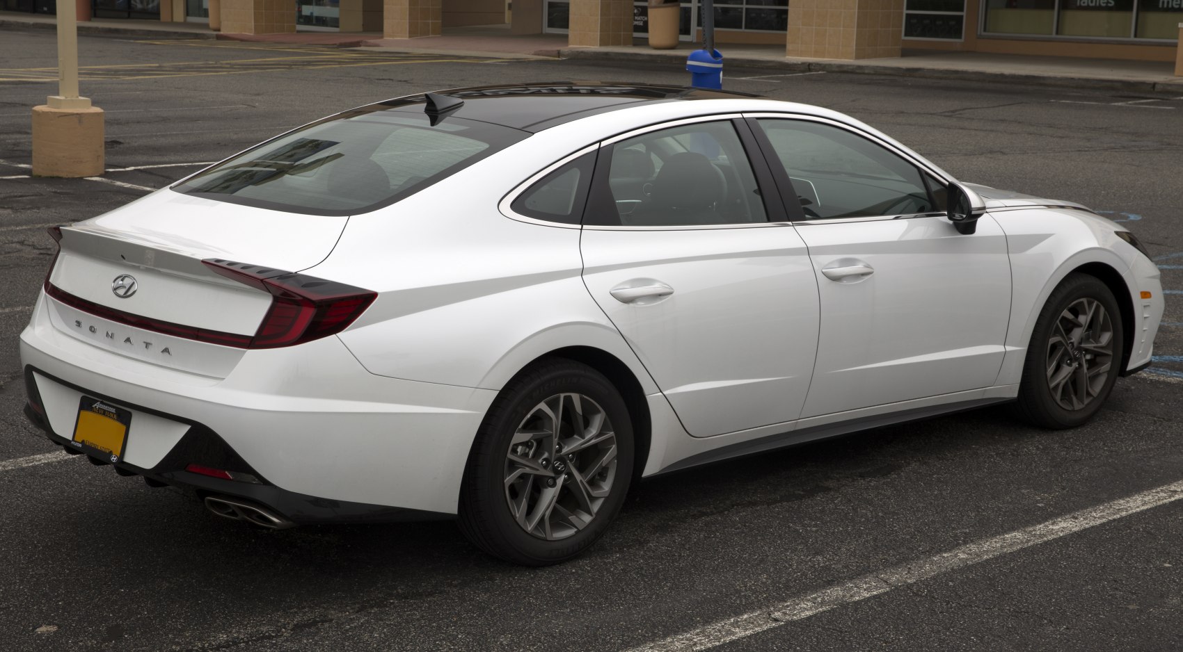 White sedan showing rear side with sleek design, tail lights, and alloy wheels