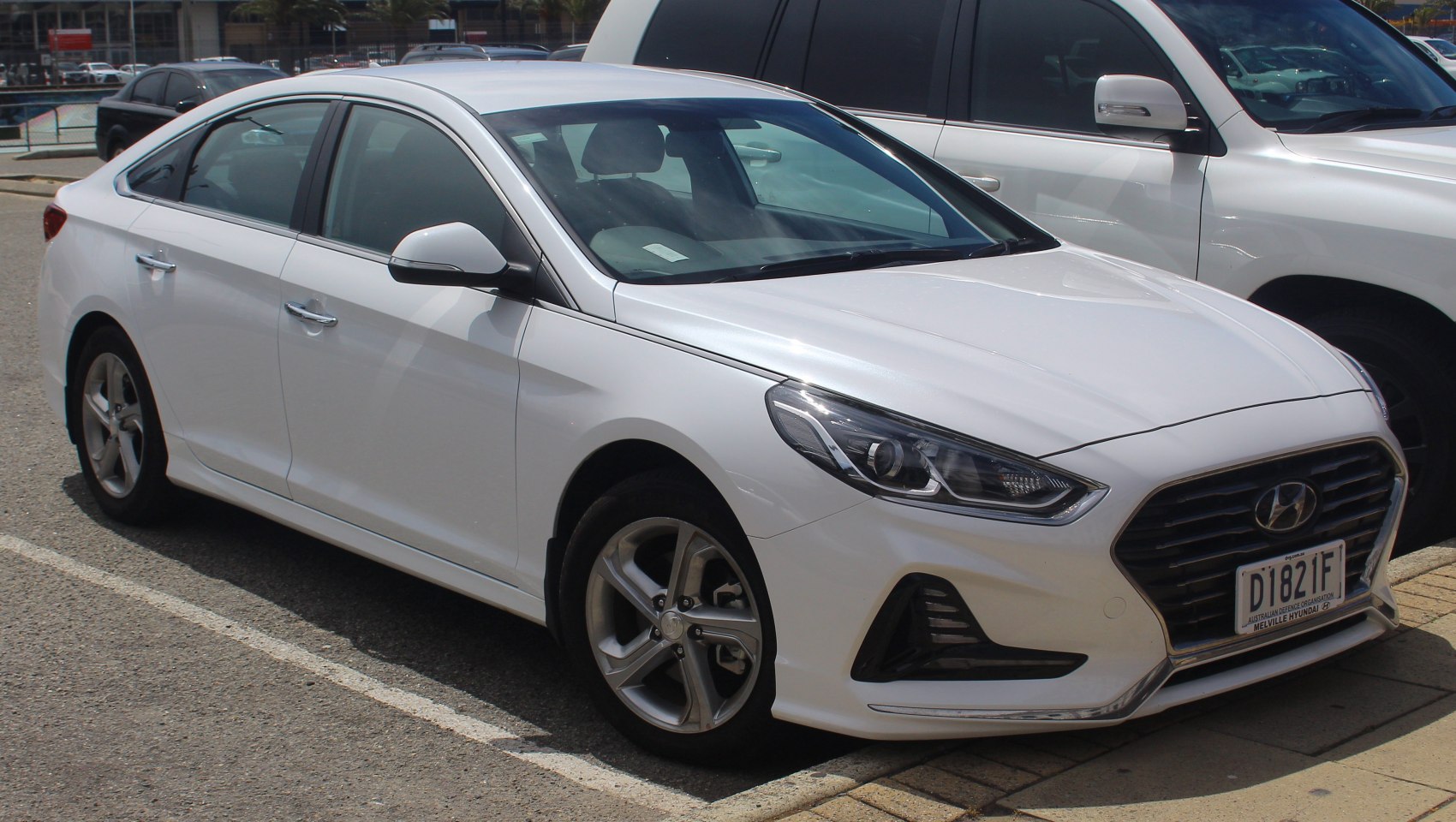 White sedan showing front-side with detailed headlights and grille.