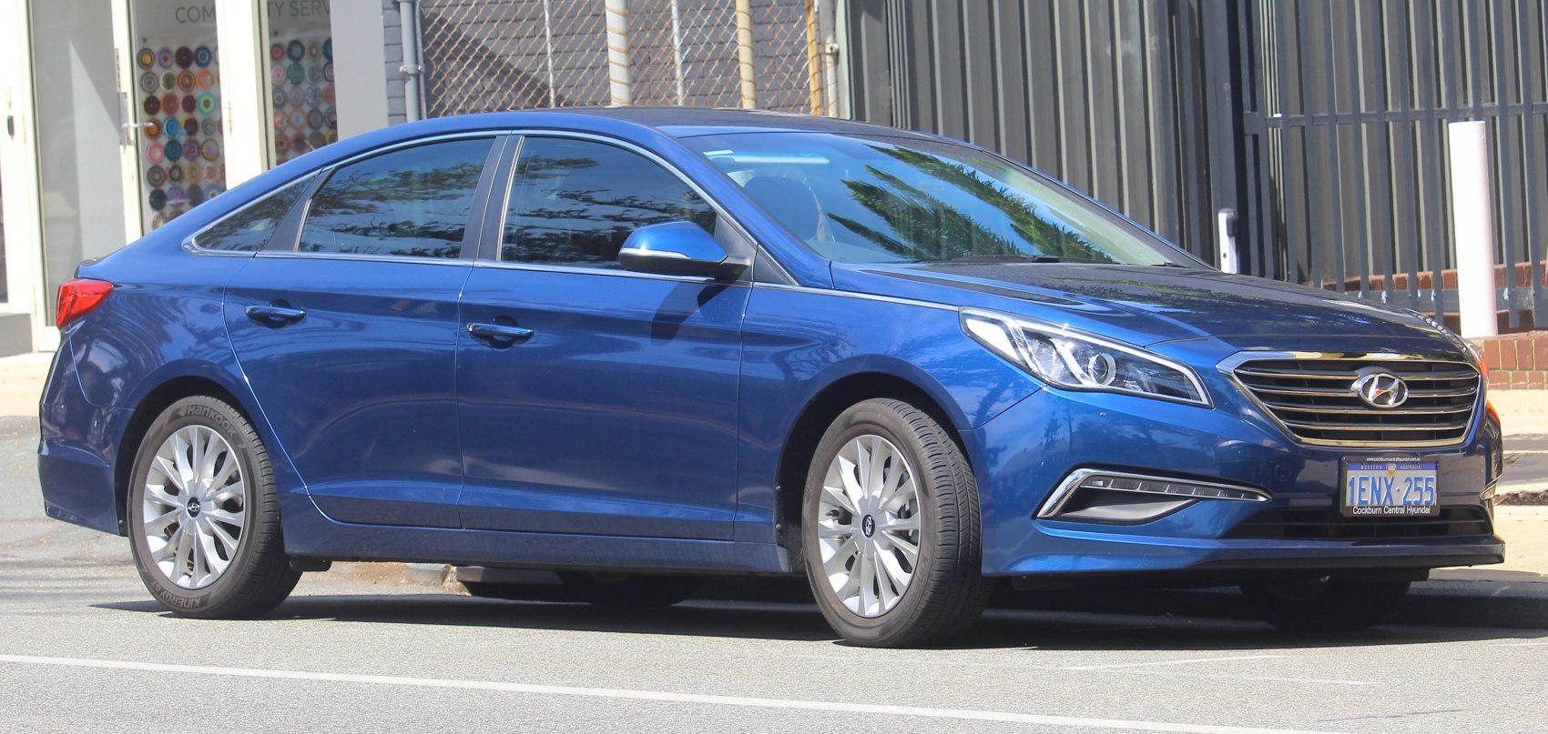 Blue sedan with alloy wheels and sleek headlights side front view