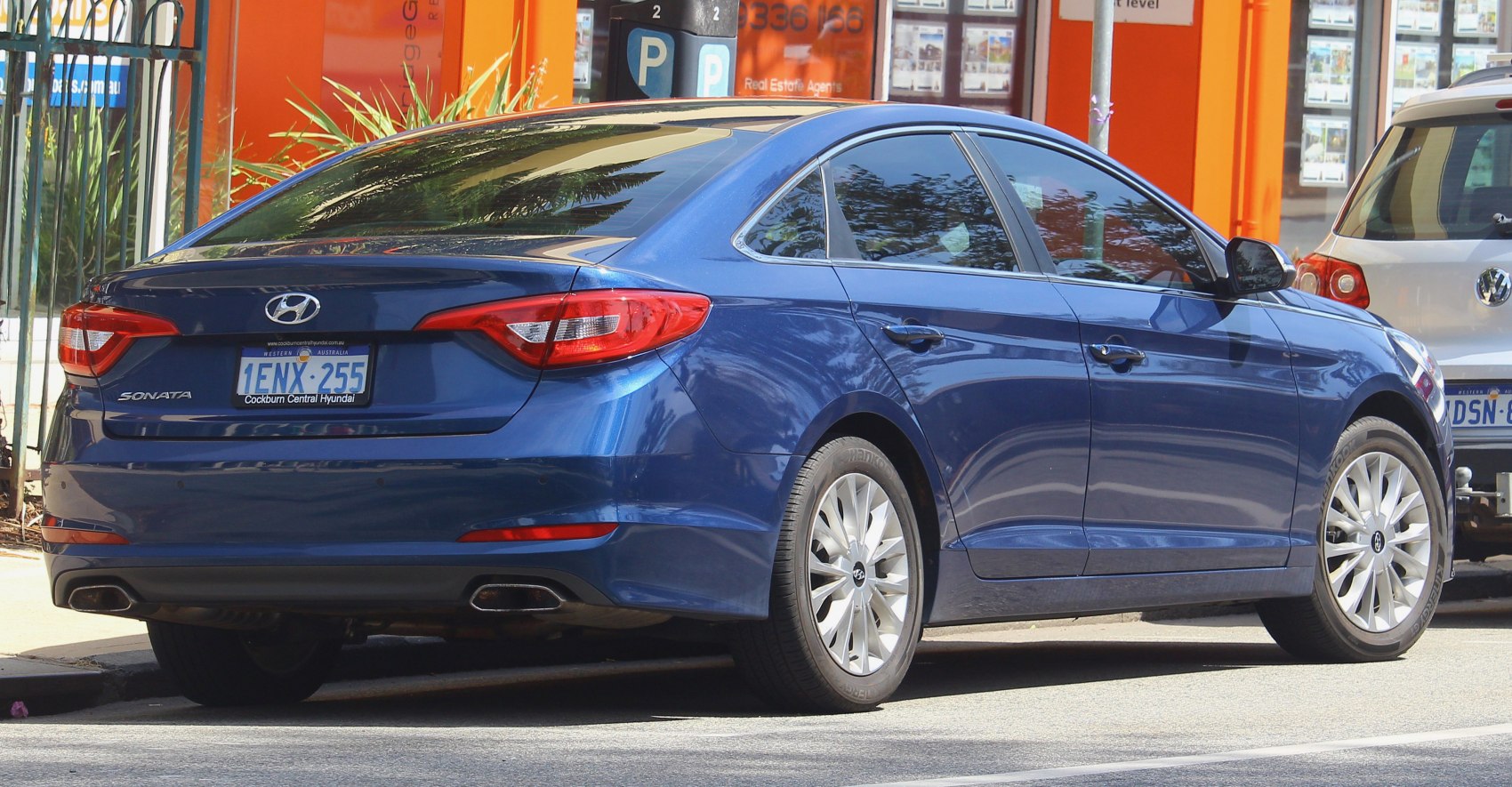 Rear and side view of blue midsize sedan with dual exhaust and alloy wheels