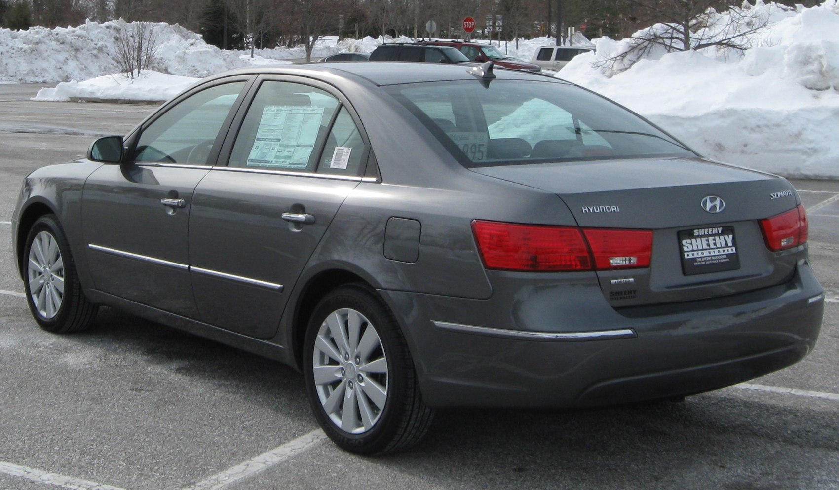 Rear side view of a gray sedan with alloy wheels and prominent tail lights.