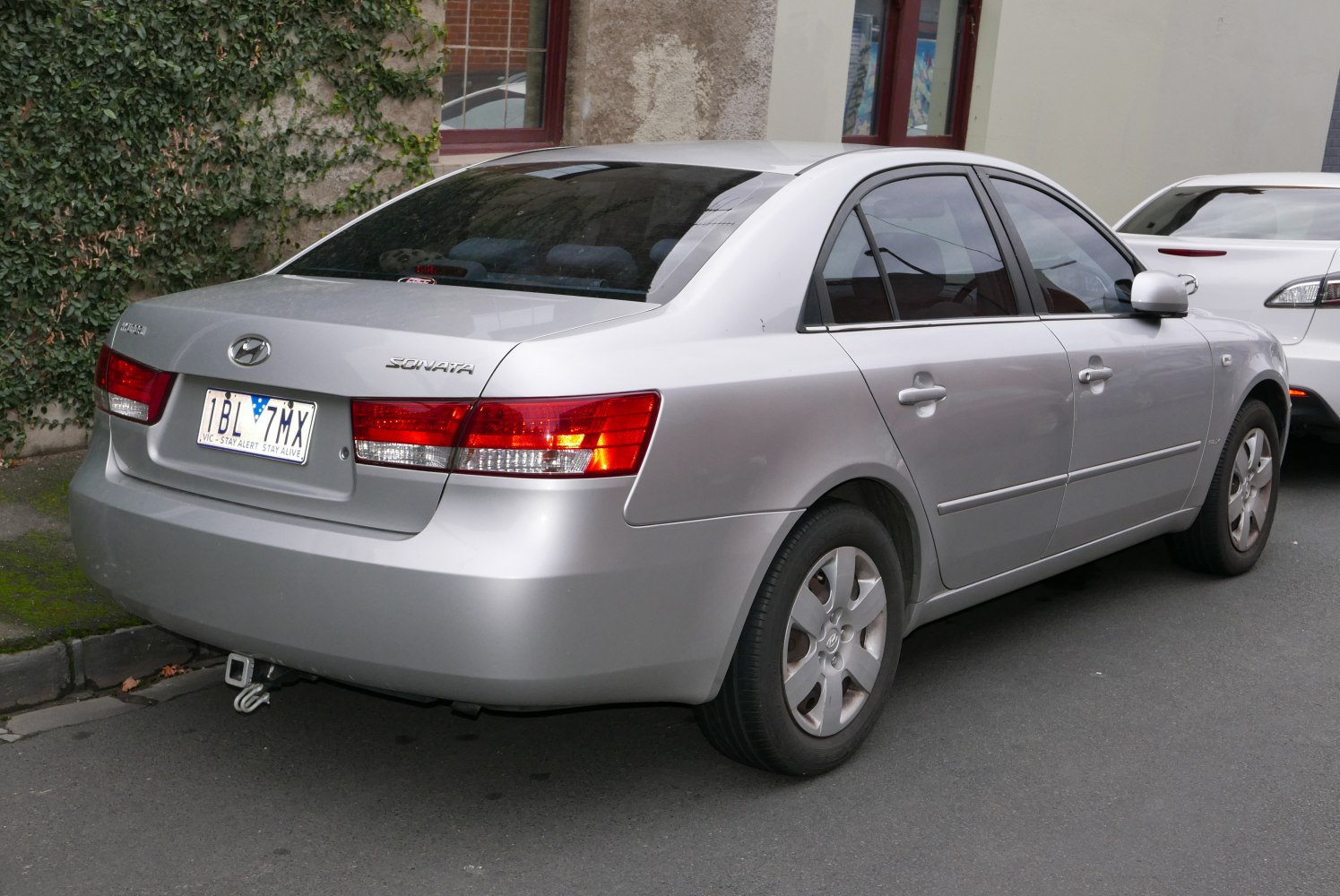 Rear side view of a silver 2005 Hyundai Sonata with visible taillights and tow hook.