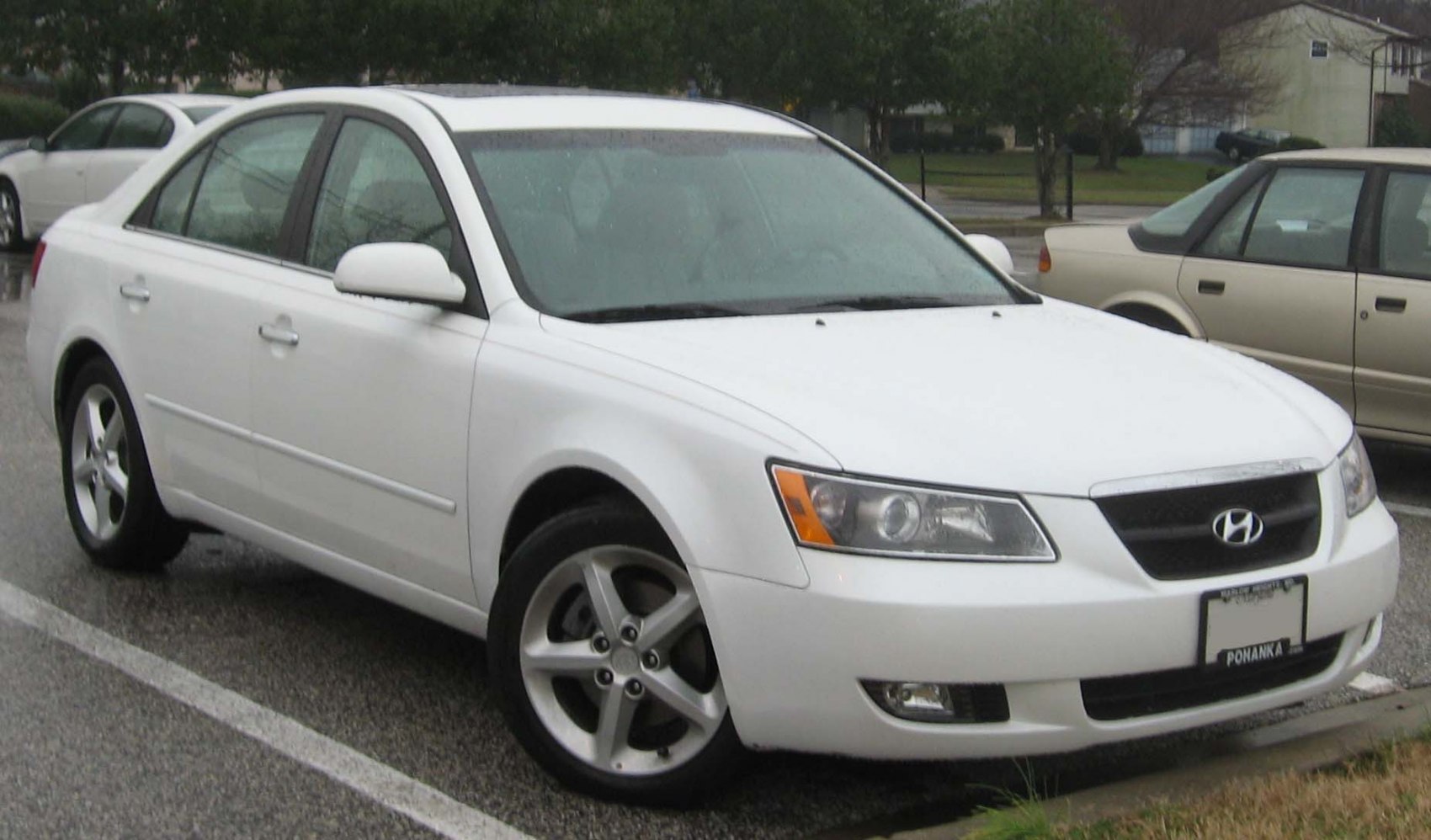White sedan showing front side with headlights and alloy wheels