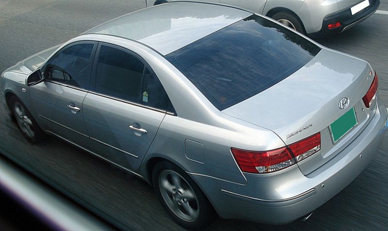Silver sedan with tinted windows and alloy wheels, rear and side view in motion