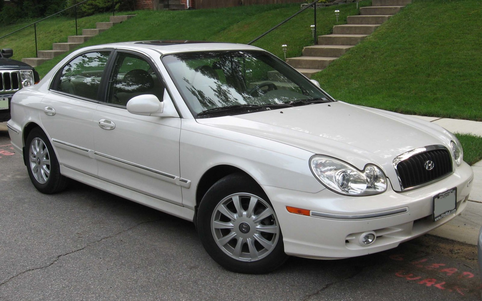 Front side view of white mid-size sedan with distinct headlights and grille