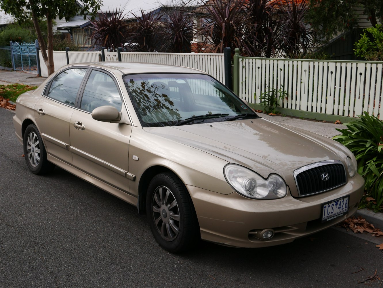 Front side view of beige midsize sedan with distinctive grille and dual headlamps
