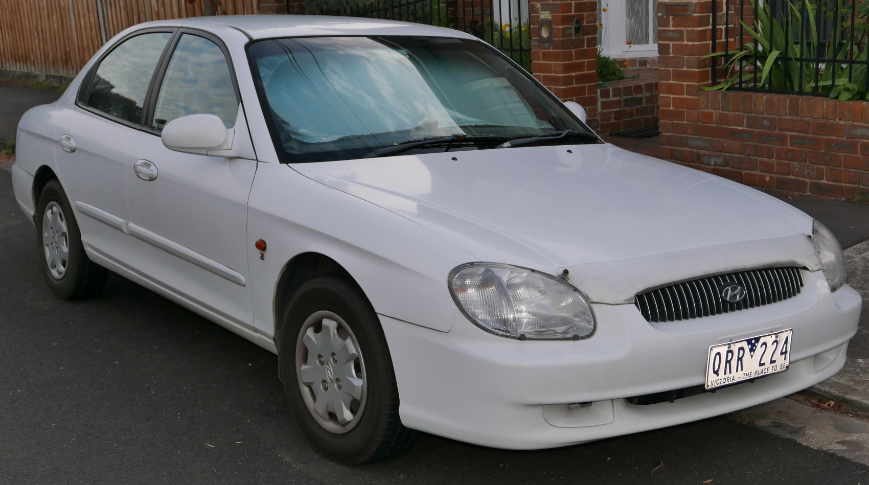 Front and side view of a white mid-90s sedan.