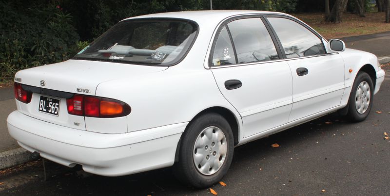 Rear-side view of 1990s four-door sedan with rounded tail lights and smooth body lines