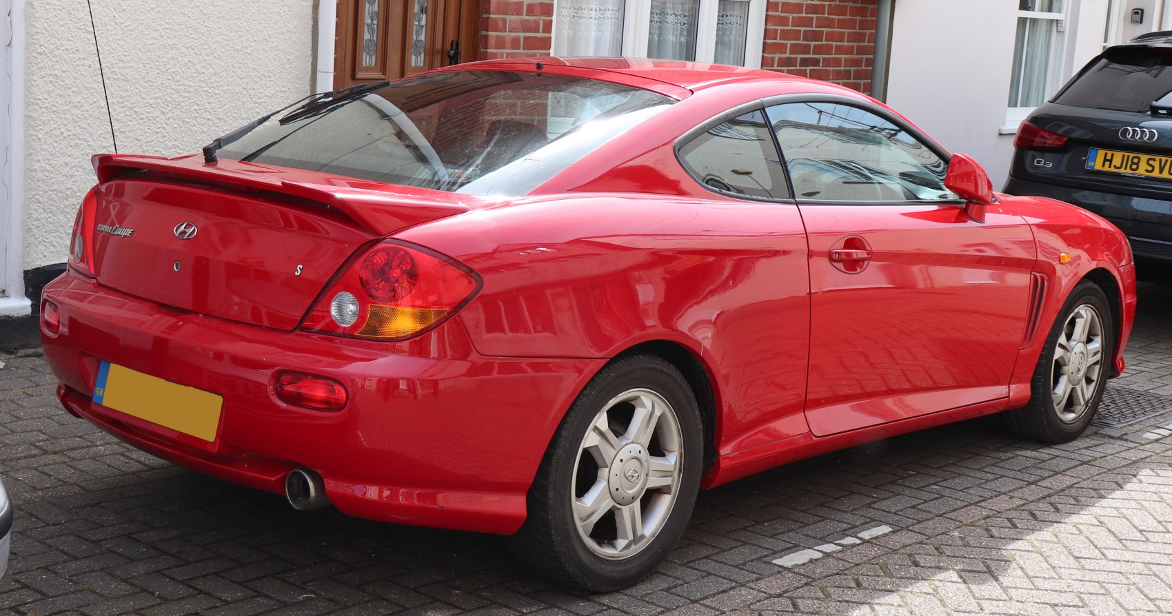 Red sporty coupe with rear spoiler and alloy wheels