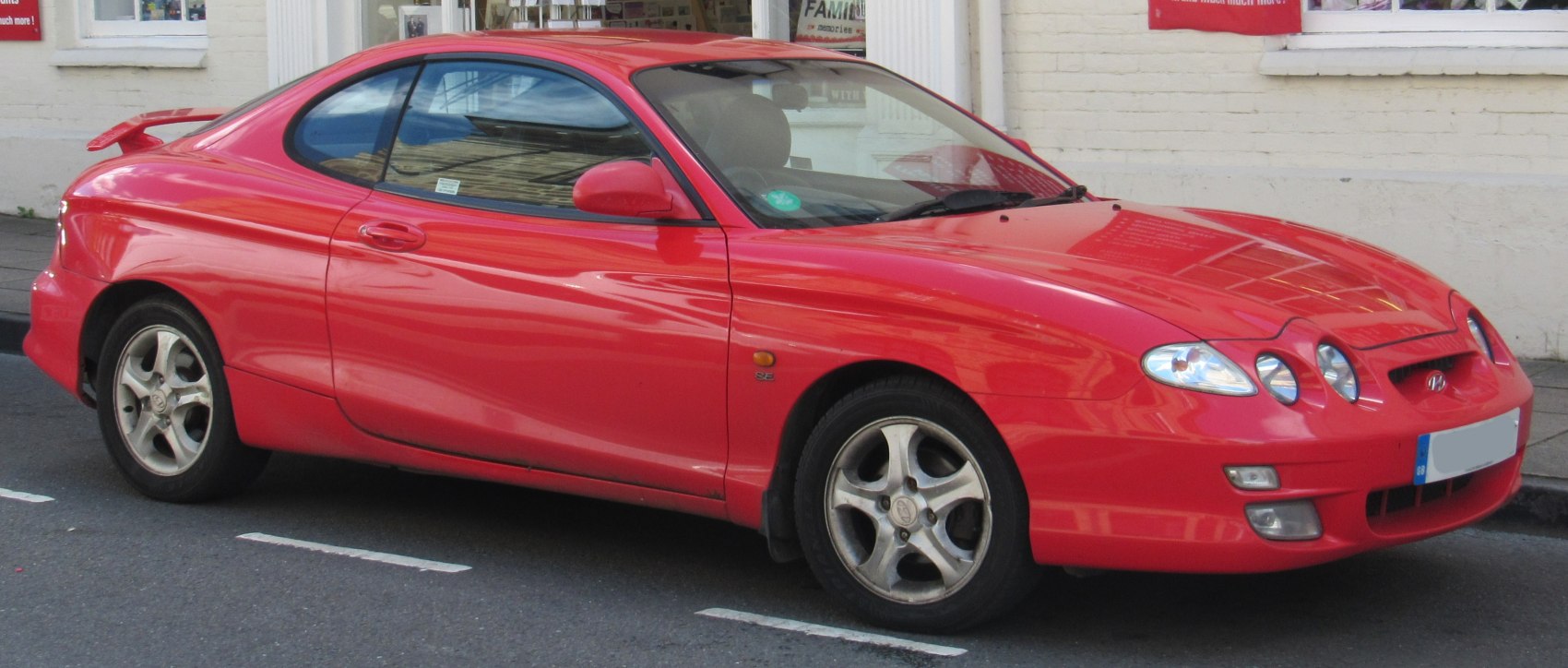Red two-door sports coupe with triple round headlights and rear spoiler
