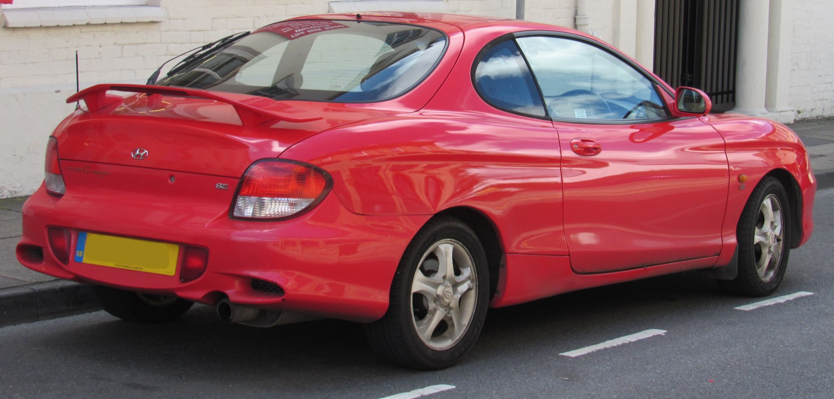 Rear view of a red coupe with spoiler and distinctive taillights