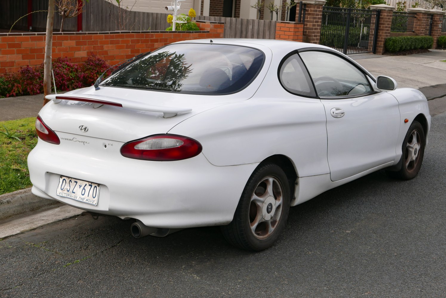 White sporty coupe rear side with spoiler and rounded taillights