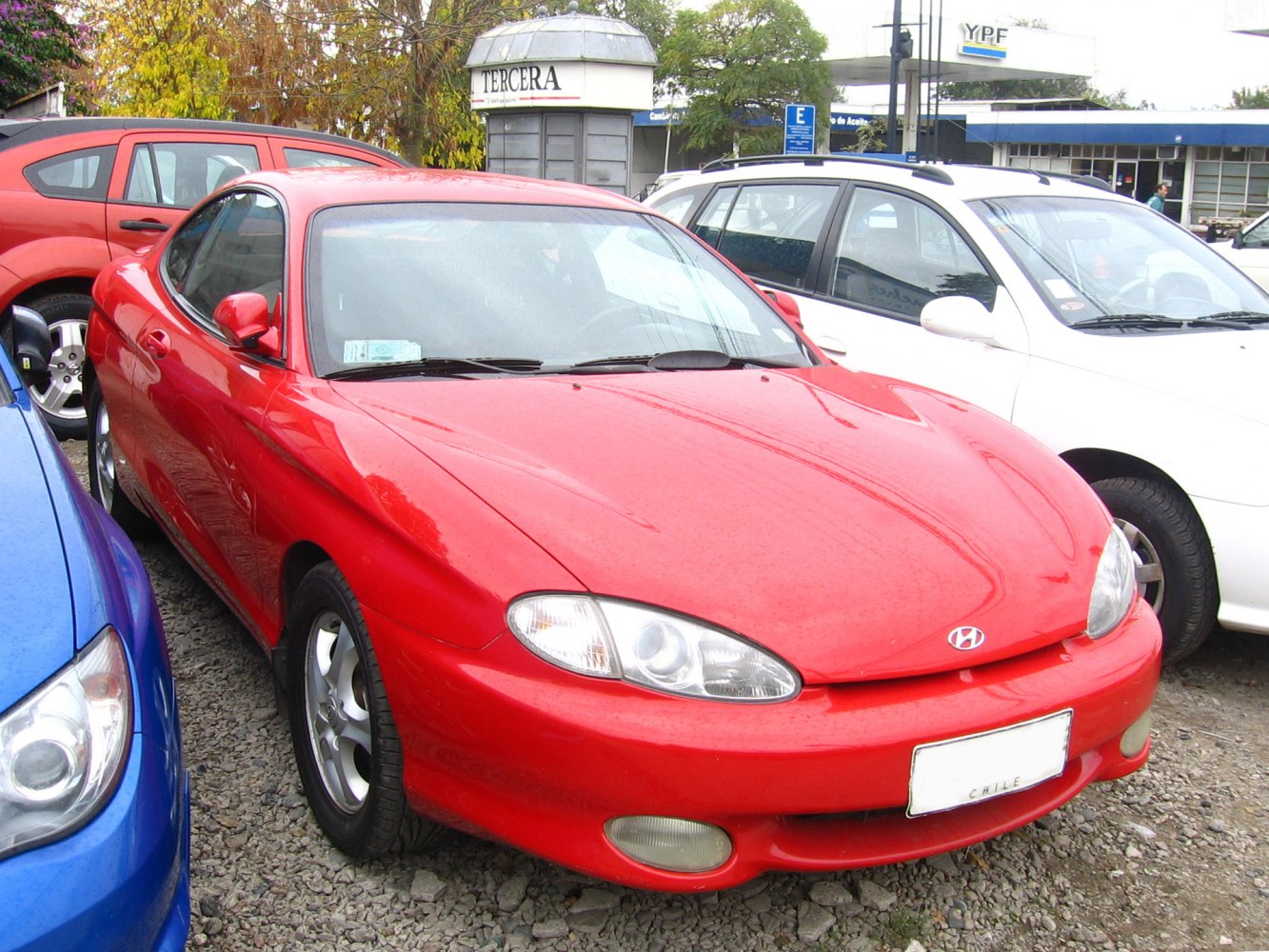 Sleek red sports coupe front with distinctive headlights and smooth contours