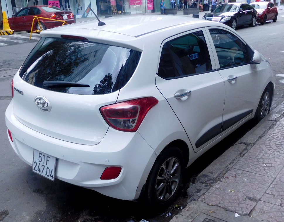 Rear side view of white hatchback with distinct tail lights and rear window wiper